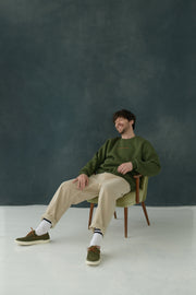 Male model wearing Urban Green & Orange Sweatshirt, sitting on a chair