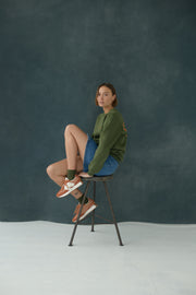 Female model wearing Urban Green & Orange Sweatshirt, sitting on a chair
